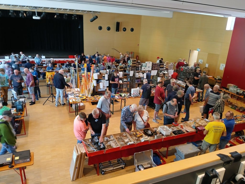 ... Auch auf dem Flohmarkt war bis nach 09.00 Uhr wenig los. Aber dann ging es dort so richtig rund. Und damit wären wir auch schon beim Amateurfunk-Flohmarkt. Während alles zunächst eher gemächlich zuging, waren ab 10.00 Uhr die Gänge zwischen den Ständen sehr gut gefüllt. Im Gang vor der Bühne war richtig Betrieb . (dort hatte ein wohl beliebter Händler seinen Stand in voller Breitseite der Bühne) Nun es ist ja u. a. der Sinn und Zweck solcher Märkte, dass der Funkamateur seine Wünsche erfüllt bekommt und der Händler gut verkauft. ...